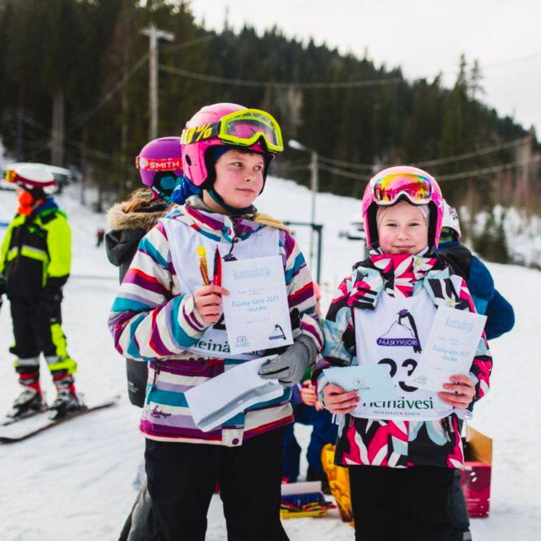 Pienet lapset lasketteluvaatteissa Heinäveden Pääskyvuoren rinnekeskuksessa Pohjoisella Saimaalla – koko perheen kohde, jossa rinteet sekä kahvila ja ravintola.