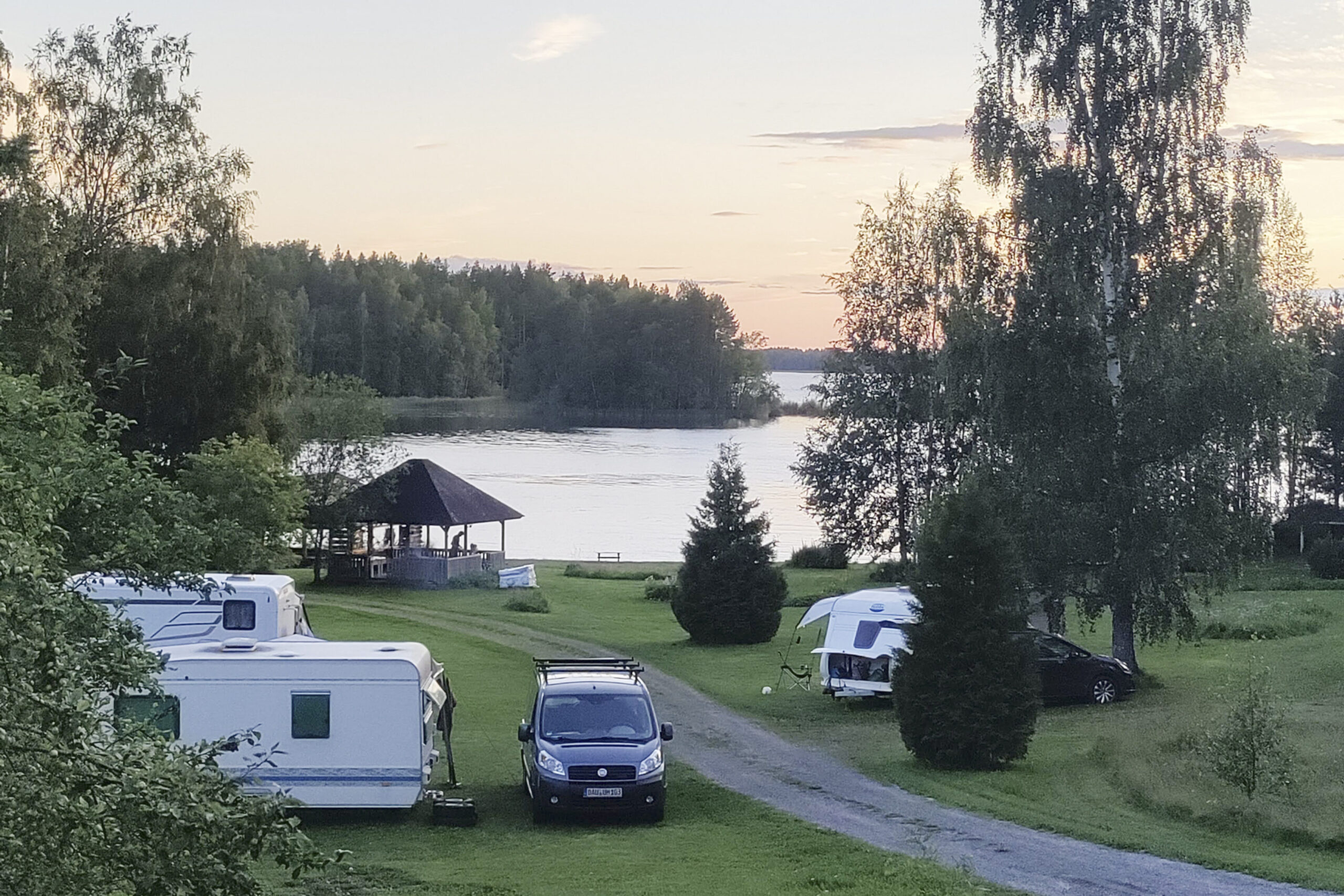 Koivuniemen leirintäalueella vaunuja kauniissa järvimaisemassa illalla.