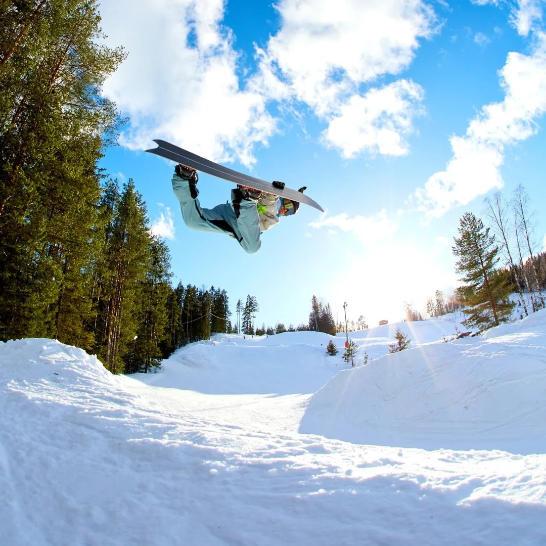 Lumilautailija ilmassa Pääskyvuoren rinnekeskuksessa Heinävedellä – talviaktiviteetteja lapsiperheille.