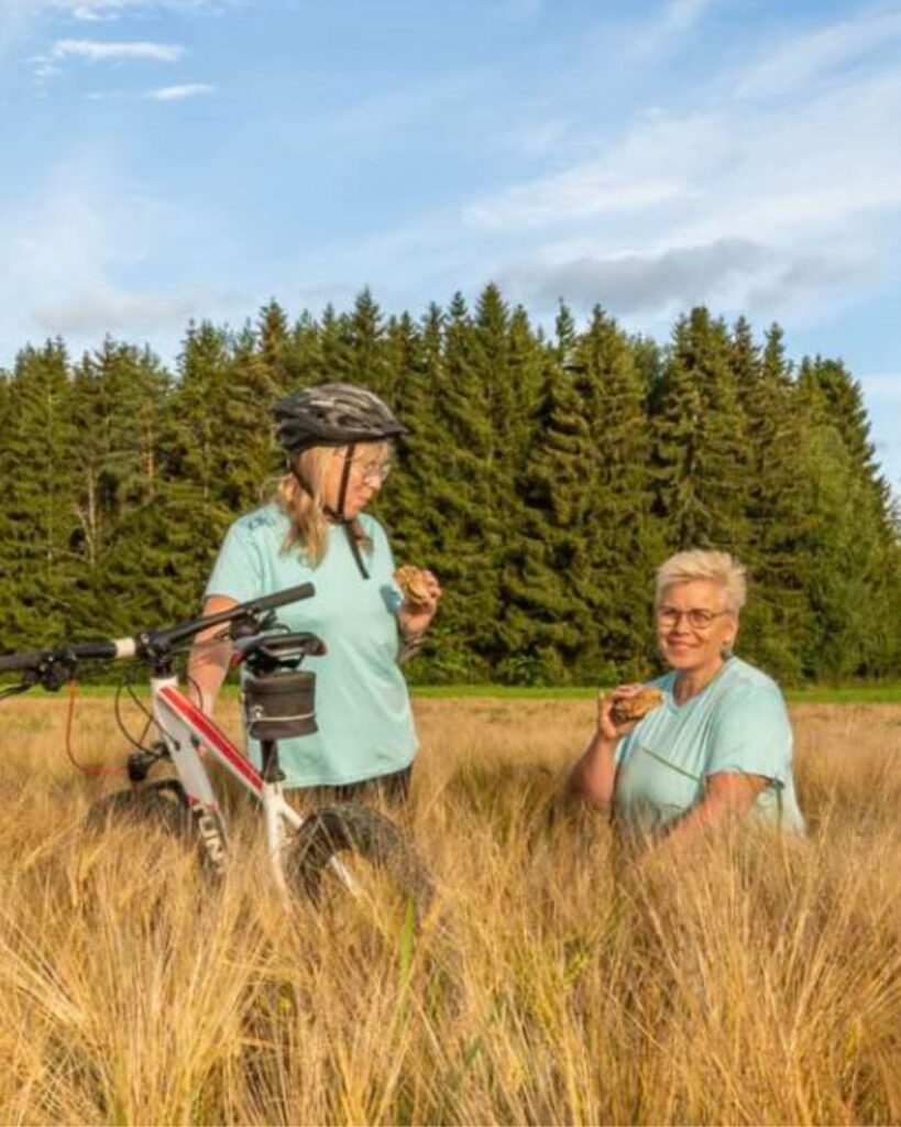 Kaksi naista viljapellolla – Elokinkerin hapanjuurileivonta-, liikunta- ja hyvinvointikurssit.