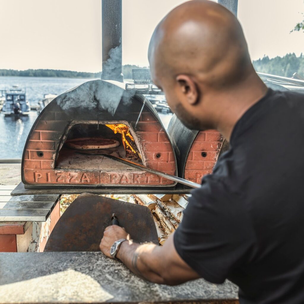Pizzaa laitetaan oikealla tulella lämpiävään uuniin Saariston Puodissa.