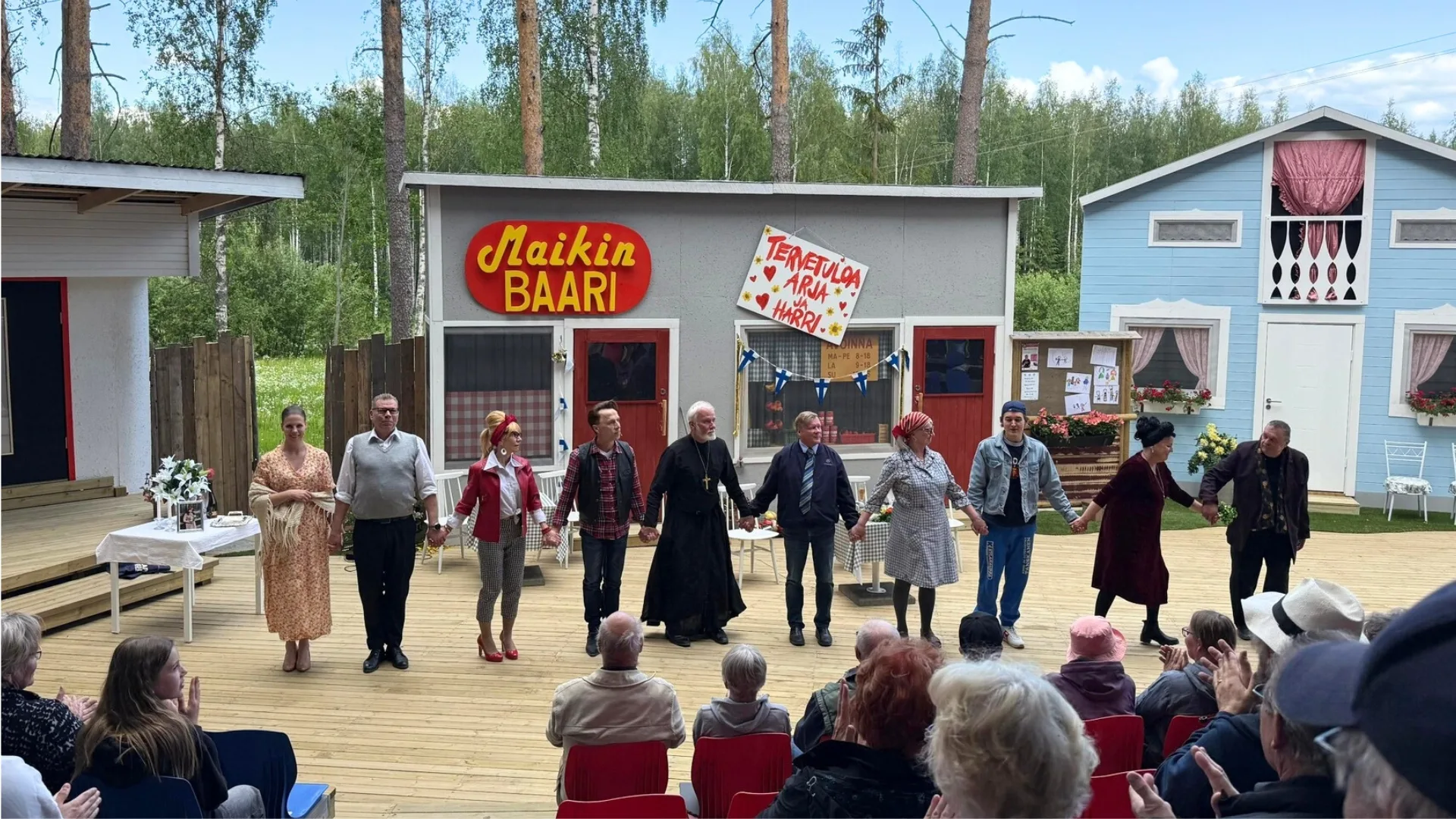 Näyttämö täynnä näyttelijöitä kiittämässä yleisöä Maikin baarin lavasteilla – paikallista kulttuuria Pohjois-Karjalassa.