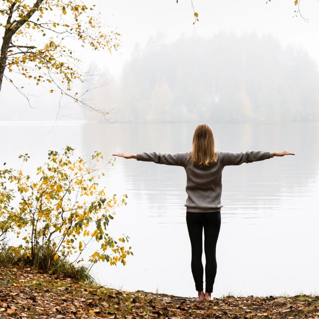 Woman standing with arms at sides in an atmospheric autumn lake landscape in North Karelia – experience guided tours in Northern Saimaa.