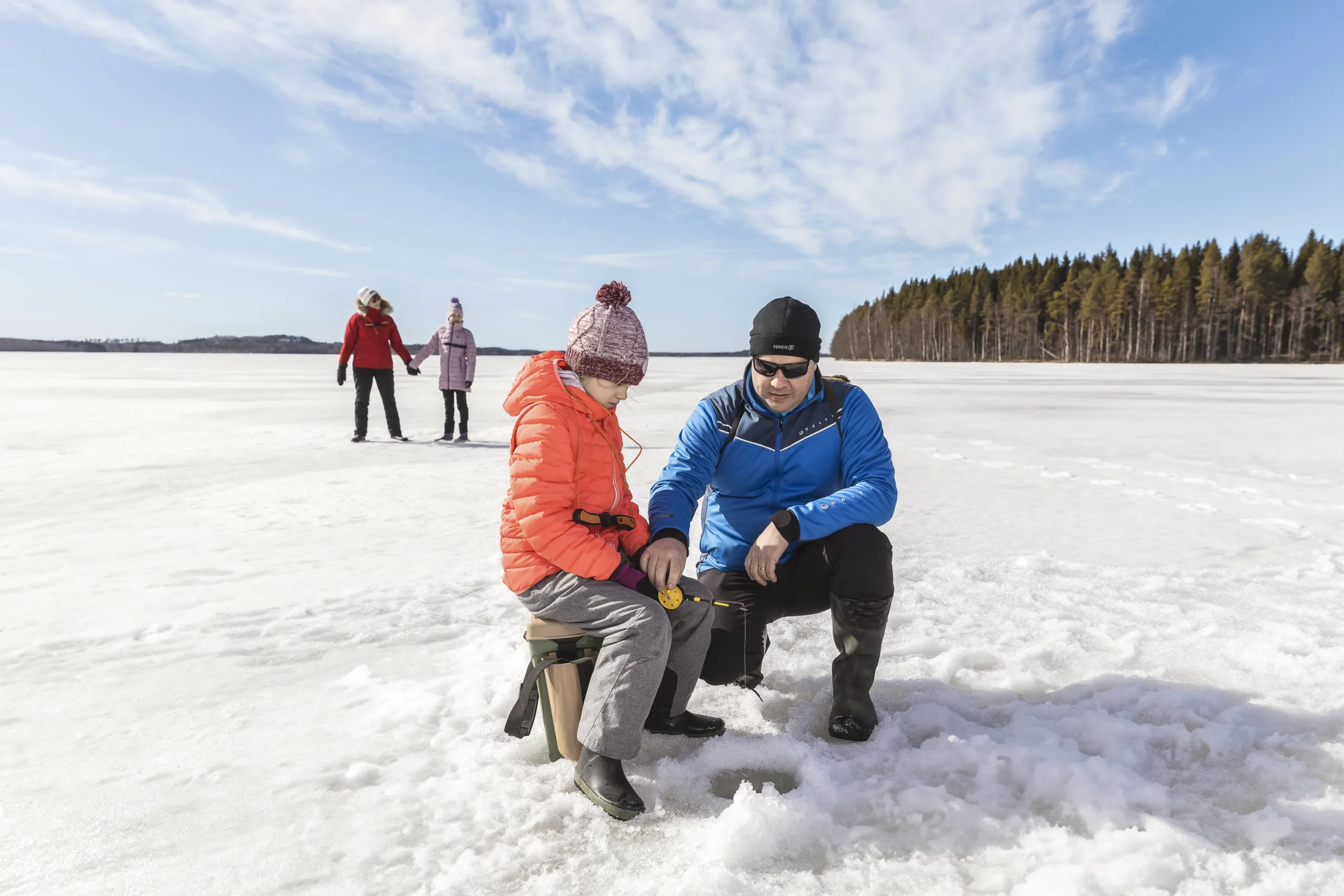 Perhe pilkillä, mies kairaa jäähän reikää lapsen kanssa Pohjois-Karjalassa – vastuullisia perheaktiviteetteja ilman kalastuslupaa.