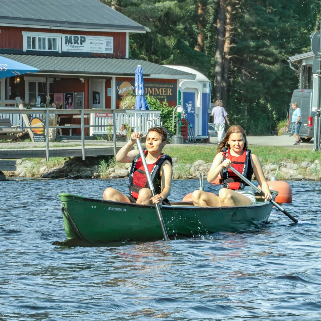 Nuoripari meloo Liperin Kirkkolahdessa, taustalla satama ja ravintola – vastuullisia reittejä lähellä Koli ja Joensuu.
