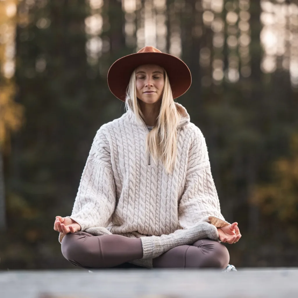Nuori nainen jooga-asennossa syksyisessä metsässä Pohjoisella Saimaalla – luonnossa toteutettavia, vastuullisia ohjelmapalveluja.