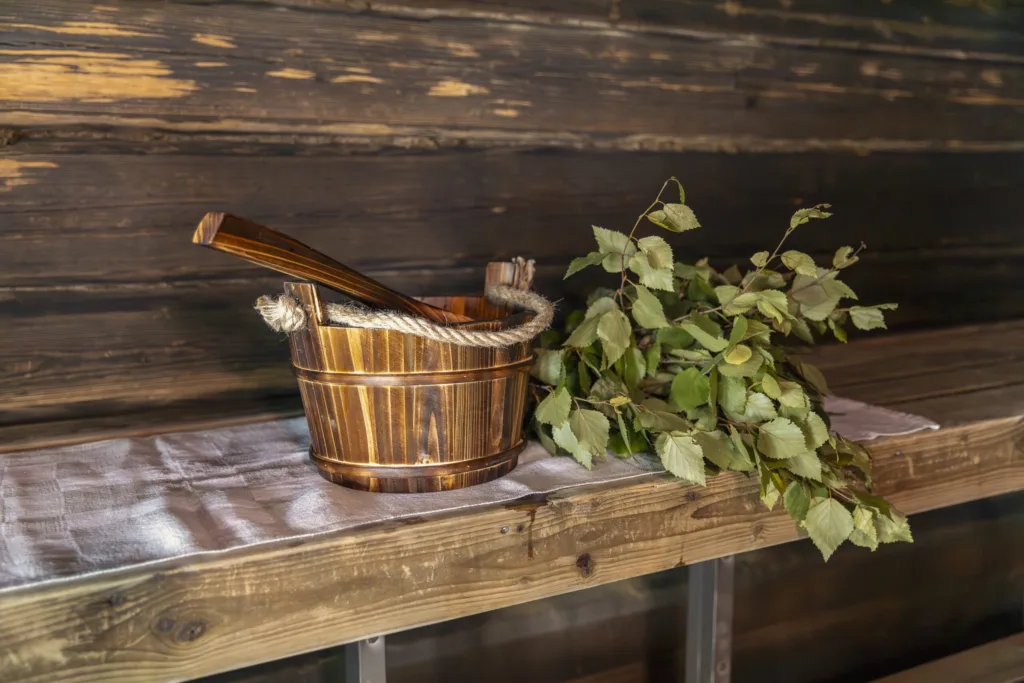 Saunan lauteet, joiden päällä ovat vesikiulu ja vasta – hyvinvointia ja luonnonläheistä saunomista Pohjoisella Saimaalla.